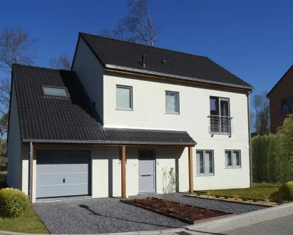 Construction neuve d’une maison moderne avec garage intégré et bardage clair